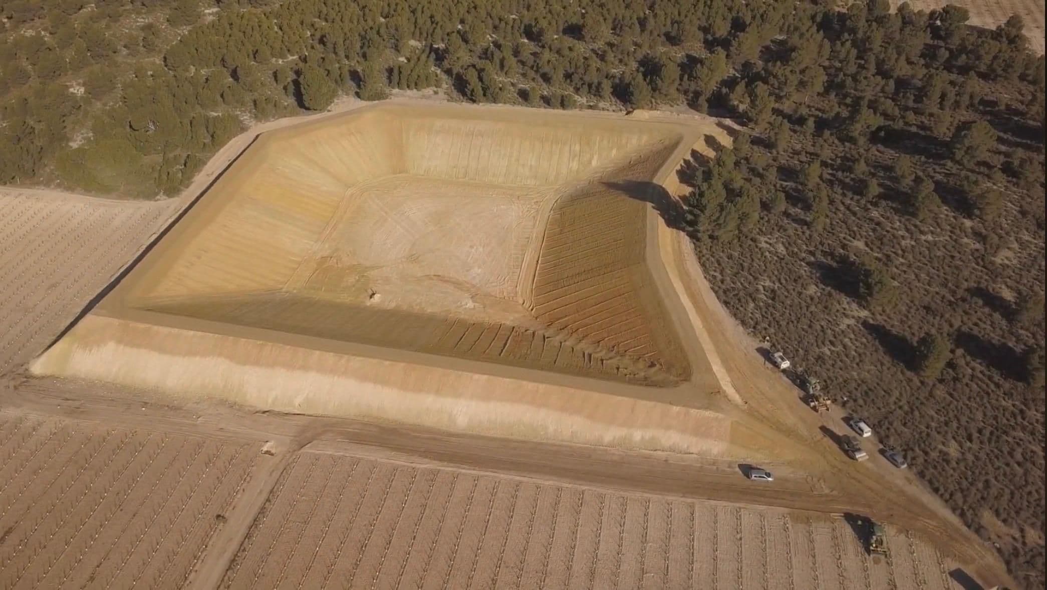 Los taludes perfilados y el fondo del vaso refinado, con la pista de coronación cerrada y las máquinas aparcadas al borde del pinar