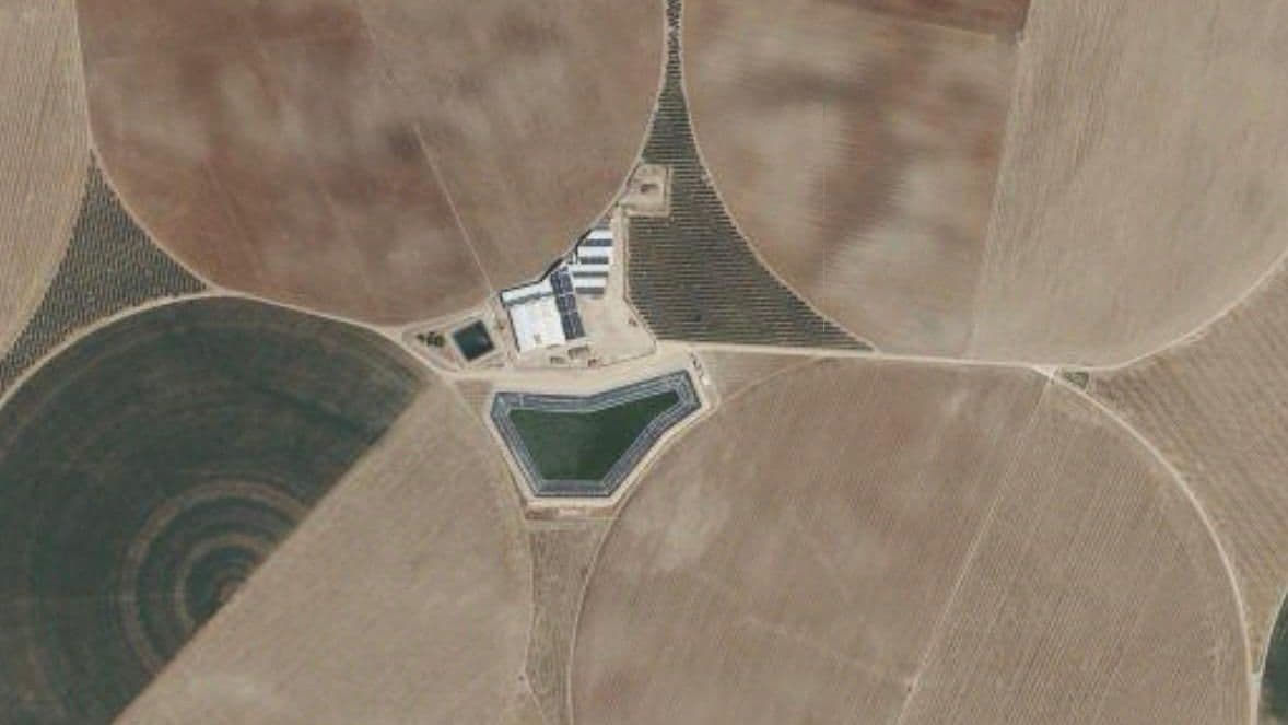 La balsa terminada vista desde más arriba, entre los círculos de riego de los pívots y con las naves de la finca justo al norte
