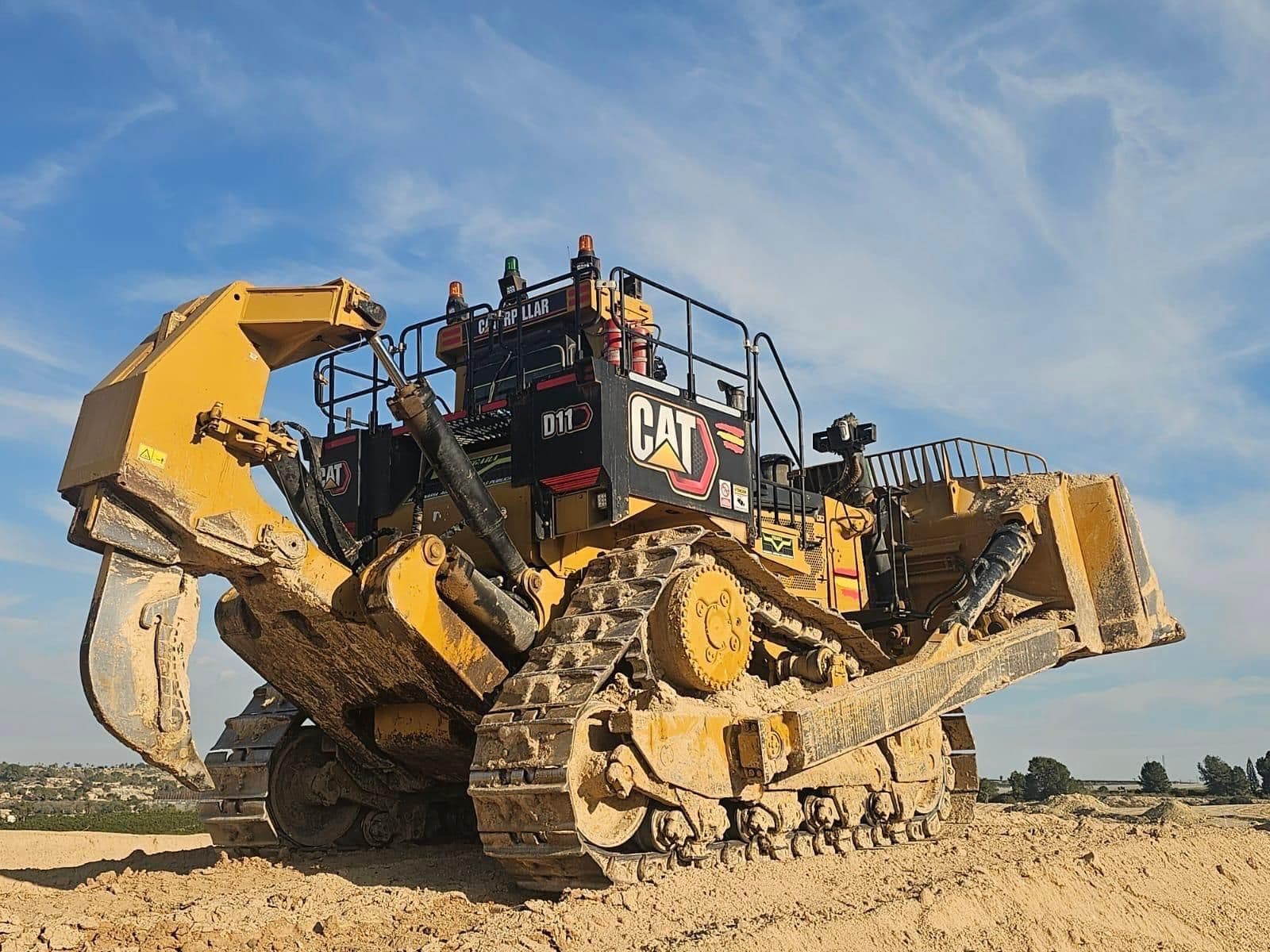 Bulldozer Caterpillar D11 de Tractores Vegara visto en contrapicado contra el cielo, sobre el terreno movido